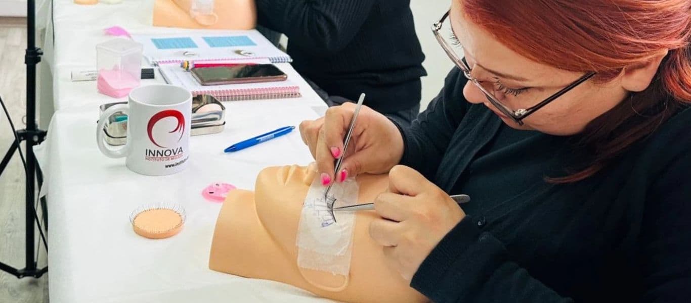 Alumna de curso de extensión de pestañas realizando práctica sobre maniqui