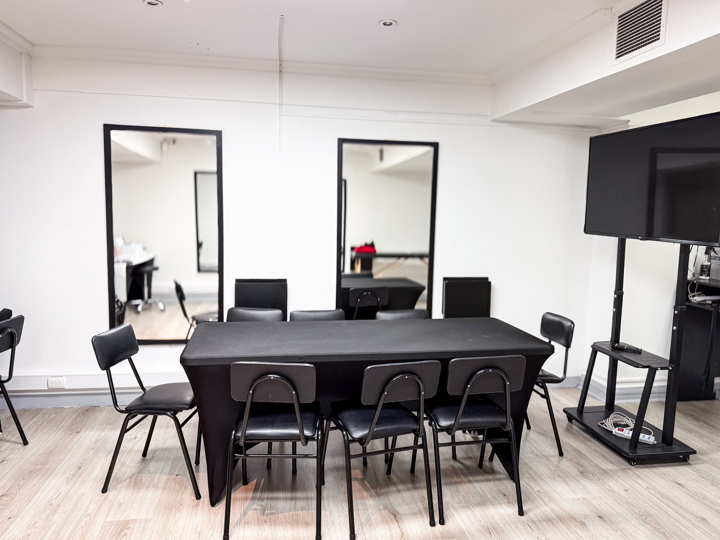 Sala de teoría con mesa, espejos y pantalla en la sede Santiago